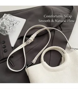 Detail der weißen Handtasche mit Litschi-Muster, geflochtenem Ringgriff und Schultergurt
