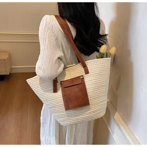 Vue détaillée du sac cabas en paille beige avec poche en cuir marron et rivets