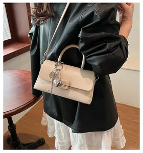 Détail du sac crème avec breloques cœur et clé et texture tissée élégante sur le cuir