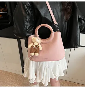 Detail van roze emmer-tas met geweven handvat en pluchen beer hanger voor damesmode