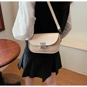 Detail of beige saddle bag with woven texture, silver G-buckle, and slim shoulder strap