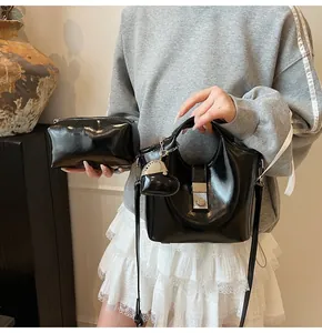 Detalle del bolso tipo cubo negro brillante y estuche con un colgante de corazón metálico