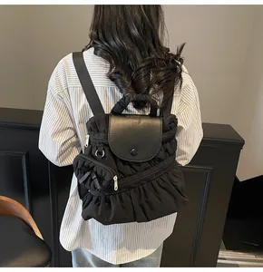 Détail du sac à dos plissé noir sur mannequin montrant la taille et le nylon doux