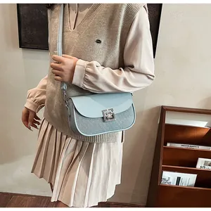 Detail of light blue saddle bag with woven texture and silver metallic lock buckle