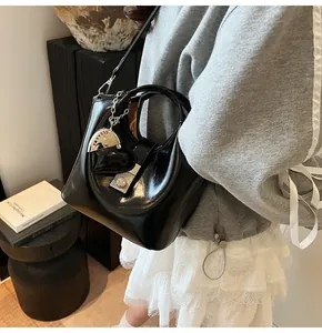 Detalle del bolso cubo negro brillante con colgante de corazón y cierre metálico