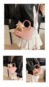 Detail van roze leren tas met geweven handvat en pluche beer als accessoire