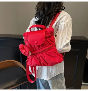 Détail d'un sac à dos plissé rouge avec pochette assortie porté par un modèle