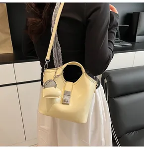 Detalle del bolso tipo cubo de cuero amarillo con colgante de corazón y cierre de metal