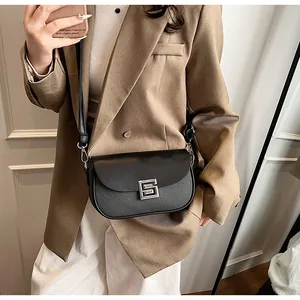 Detail of a minimalist black saddle bag with silver buckle worn by a model in a blazer