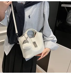 Detalle de bolso tipo cubo blanco con colgante de corazón y cierre metálico plateado