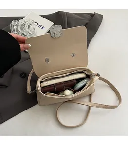 Détail de l'intérieur spacieux du sac bandoulière beige avec objets du quotidien
