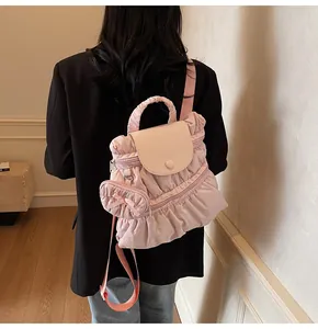 Détail du sac à dos plissé rose avec volants et breloque cœur sur un blazer noir élégant