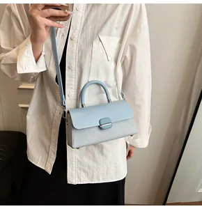 Détail du sac à main bleu ciel avec texture tissée et rabat en cuir lisse élégant