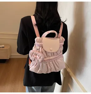 Sac à dos plissé rose clair avec breloque nœud en forme de cœur porté par un mannequin