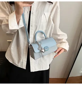 Détail du sac bandoulière bleu clair avec breloque cœur argentée et boucle en métal