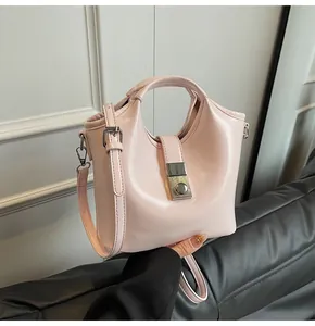 Detalle del bolso de charol rosa claro con cierre plateado y correa ajustable fina