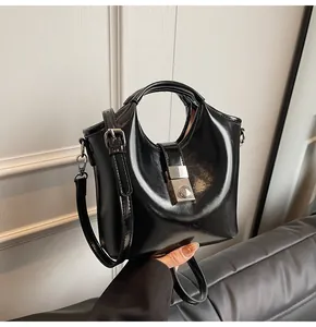 Detalle del bolso tipo cubo negro brillante con cierre metálico plateado y acabado espejo