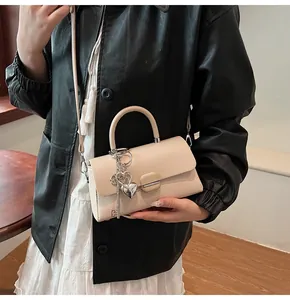 Détail du petit sac beige carré avec breloques argentées et bandoulière réglable