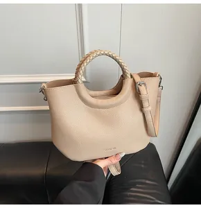 Detail van beige lychee lederen emmertas met gevlochten handvat en schouderriem