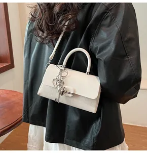 Détail du sac bandoulière blanc avec texture tressée et breloques de clés en cœur