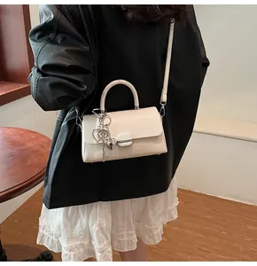 Vue détaillée du sac bandoulière en cuir crème avec breloque cœur et lanière