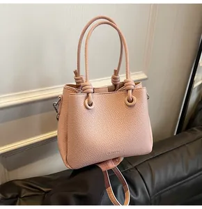 Close-up of pink litchi grain leather bucket bag with twist knot handle and brand logo