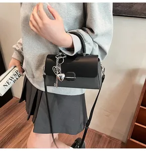 Détail d'un sac à rabat noir avec breloques en cœur et textures de matières mixtes