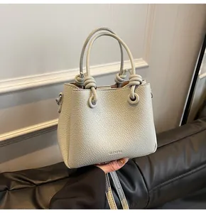 Close-up of pebble grain leather bucket bag featuring unique knotted handle and brand logo