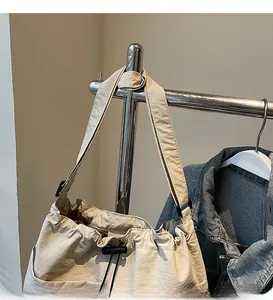 Détail du sac seau en nylon beige avec fermeture à cordon et large bandoulière