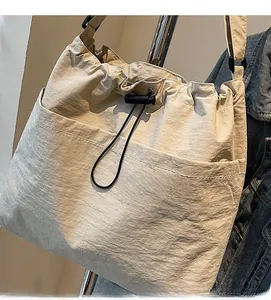 Détail du sac en nylon beige clair avec cordon de serrage et poche frontale spacieuse