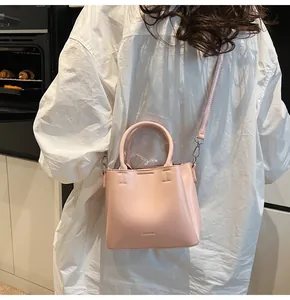 Detail shot of the pink leather bucket bag texture and embossed logo with silver hardware