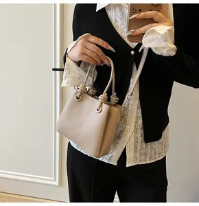Détail d'un petit sac carré en cuir beige texturé avec poignée anneau et boucles argentées