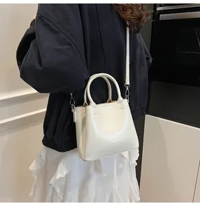 Close-up of white leather bucket bag with silver hardware and embossed brand logo