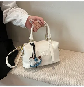 Dettaglio borsa Boston bianca con logo Muheti a rilievo e ciondolo a cavallo