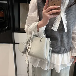 Chic light gray pebbled leather bucket bag with top handle and crossbody strap style