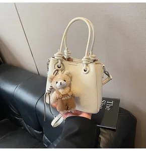 Détail du sac en cuir grainé blanc cassé avec un adorable pendentif ours en peluche