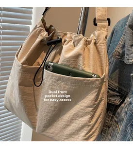 Vue détaillée du sac seau en nylon beige avec deux poches avant pour ranger un mobile