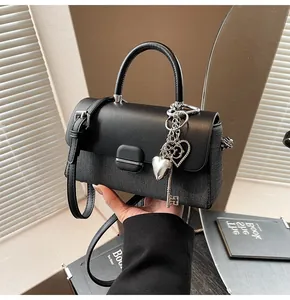 Gros plan du sac bandoulière noir avec textures mixtes et breloque cœur argentée
