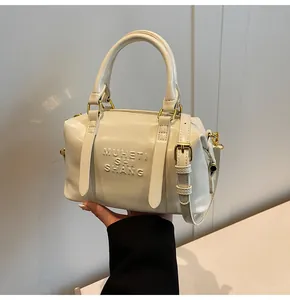 Dettaglio della borsa Boston crema in pelle lucida con scritta MUHETI in rilievo ed elegante