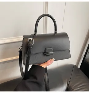 Détail d'un sac à main minimaliste en cuir noir et tissu tissé avec boucle ronde chic