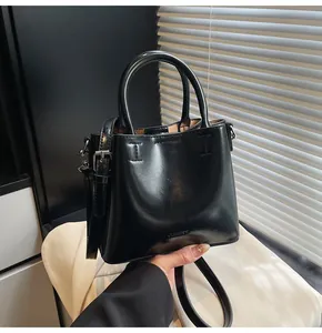 Detail of black glossy bucket bag with cylinder handle and CLEARCK logo lettering