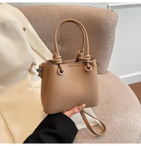 Détail du cuir texturé litchi et poignée à nœud sur un sac bandoulière beige carré