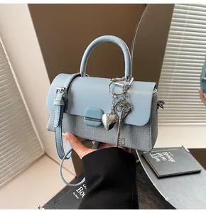 Détail du sac à main bleu clair avec breloque cœur et bandoulière en similicuir
