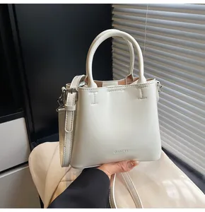 Detail of creamy white tote bag featuring double handles and clear brand logo lettering