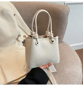 Détail du sac seau en cuir grainé crème avec décor de poignée à nœud élégant et chic