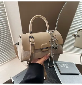 Détail du sac patchwork en tissu beige et cuir avec pendentifs cœur et clé en métal