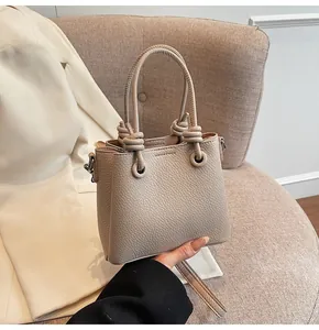 Détail de la texture cuir litchi et poignée à nœud sur le sac à bandoulière ivoire