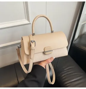 Détail du tissu texturé beige et des coutures en cuir d'un petit sac à bandoulière