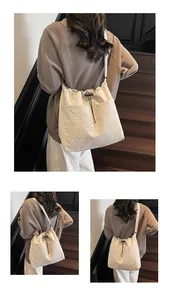 Détail du sac seau en nylon blanc cassé avec cordon de serrage, texture plissée et sangle