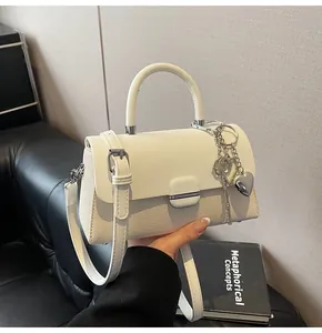 Détail du sac à bandoulière blanc texturé avec fermoir argenté et breloque en cœur